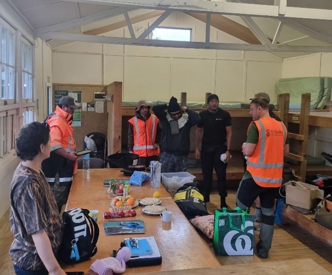 People in field gear and high vis standing in kitchen area
